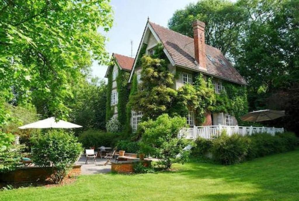 een huis met een tuin met stoelen en een parasol bij Les impressionnistes Maison de famille in Saint-Aubin-sur-Scie