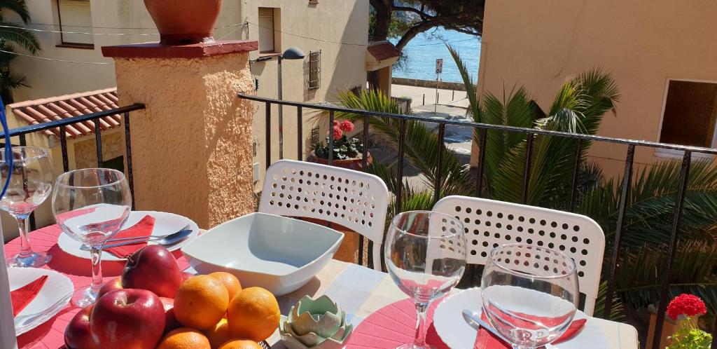 a table with wine glasses and fruit on a balcony at Casa con jardín a 30 metros de la playa. VL. in Palamós