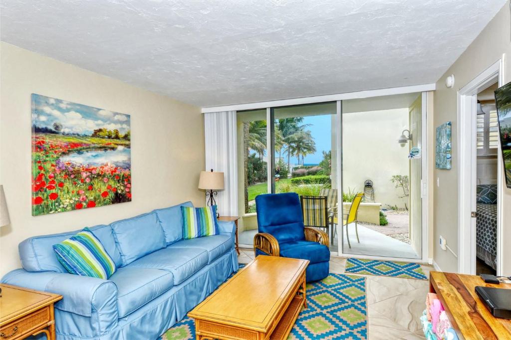 uma sala de estar com um sofá azul e cadeiras em LaPlaya 101E-Relax on your private lanai under the palms! em Longboat Key