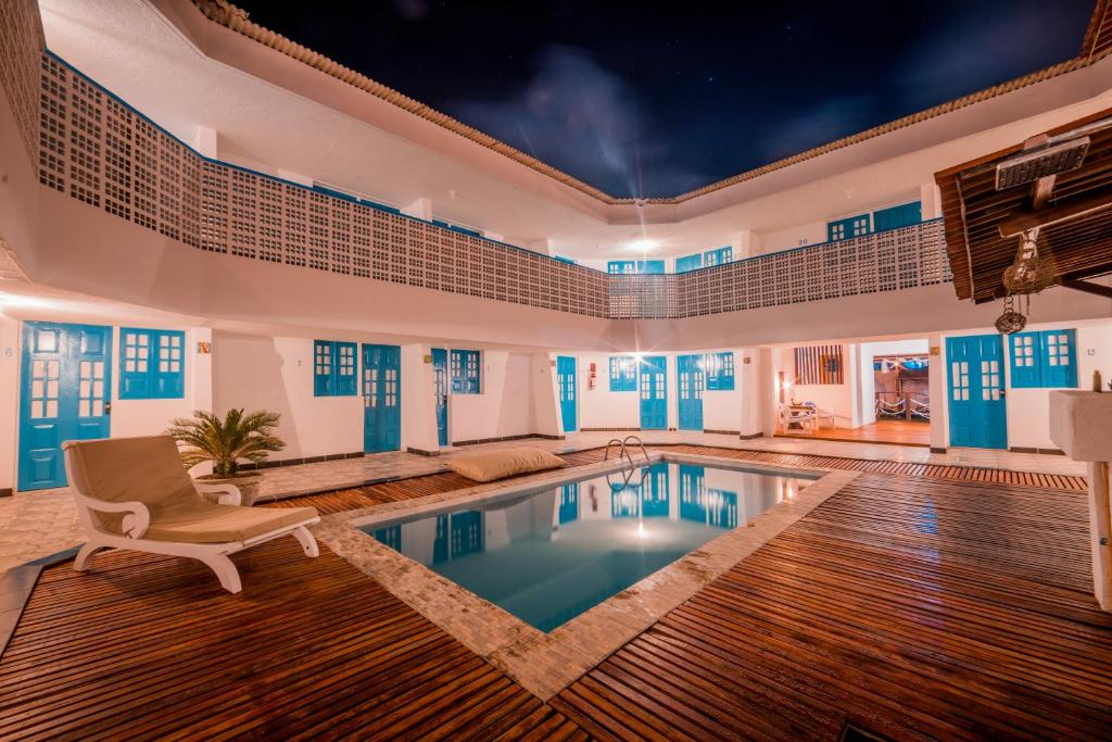 a swimming pool in a house with a couch and a chair at Pousada Santorini in Porto De Galinhas