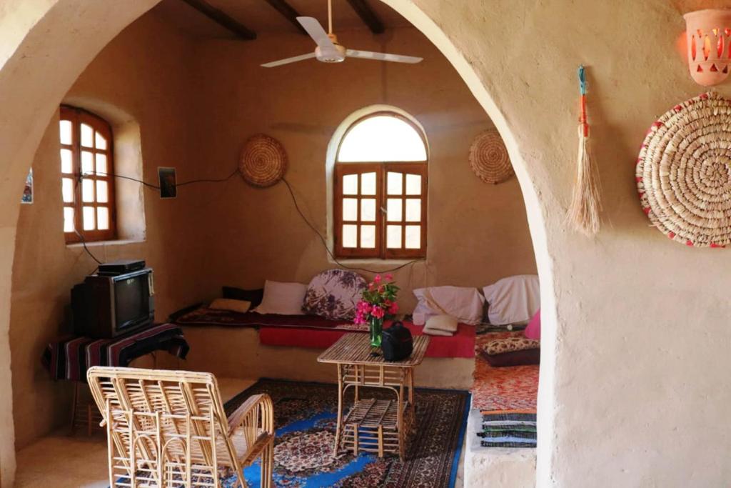 Desert Rose Guesthouse في الأقصر: غرفة معيشة مع طاولة وكراسي في غرفة