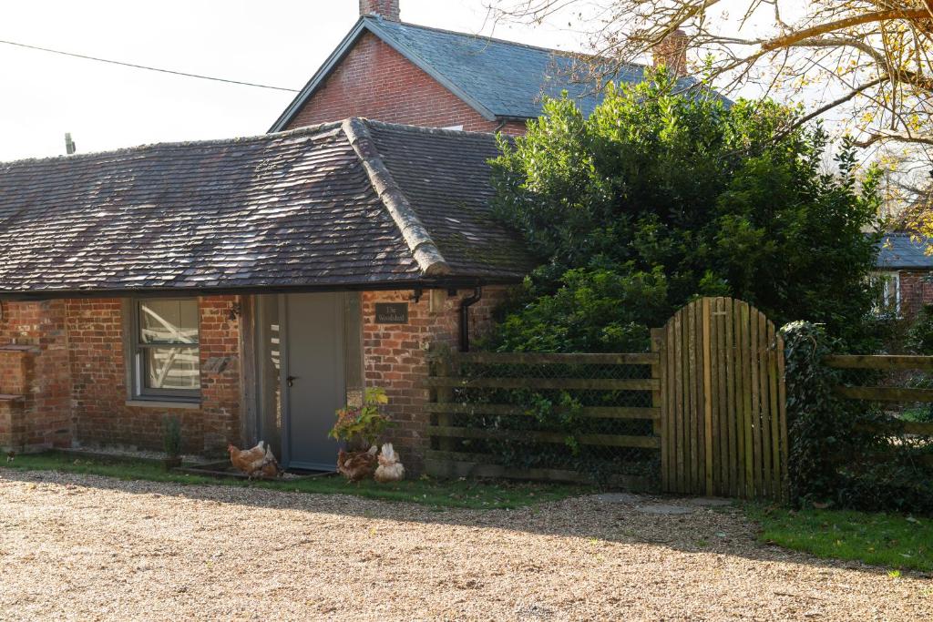 a small brick house with a wooden fence at Street Farmhouse in Godshill
