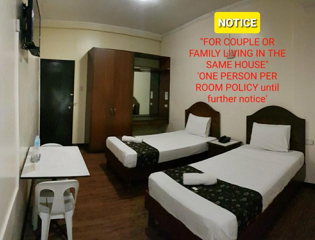 a hotel room with three beds and a sign on the wall at Grand Traveler Suite Inc in Manila