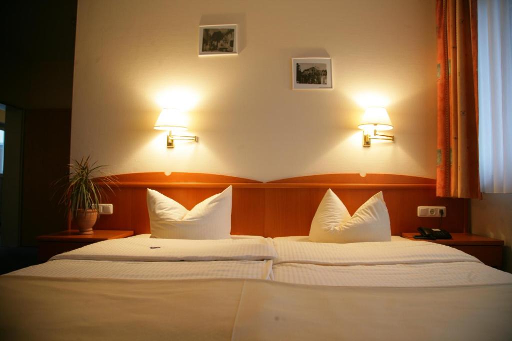 a bedroom with two beds with white pillows at Hotel Wilhelmshöhe in Neuenrade