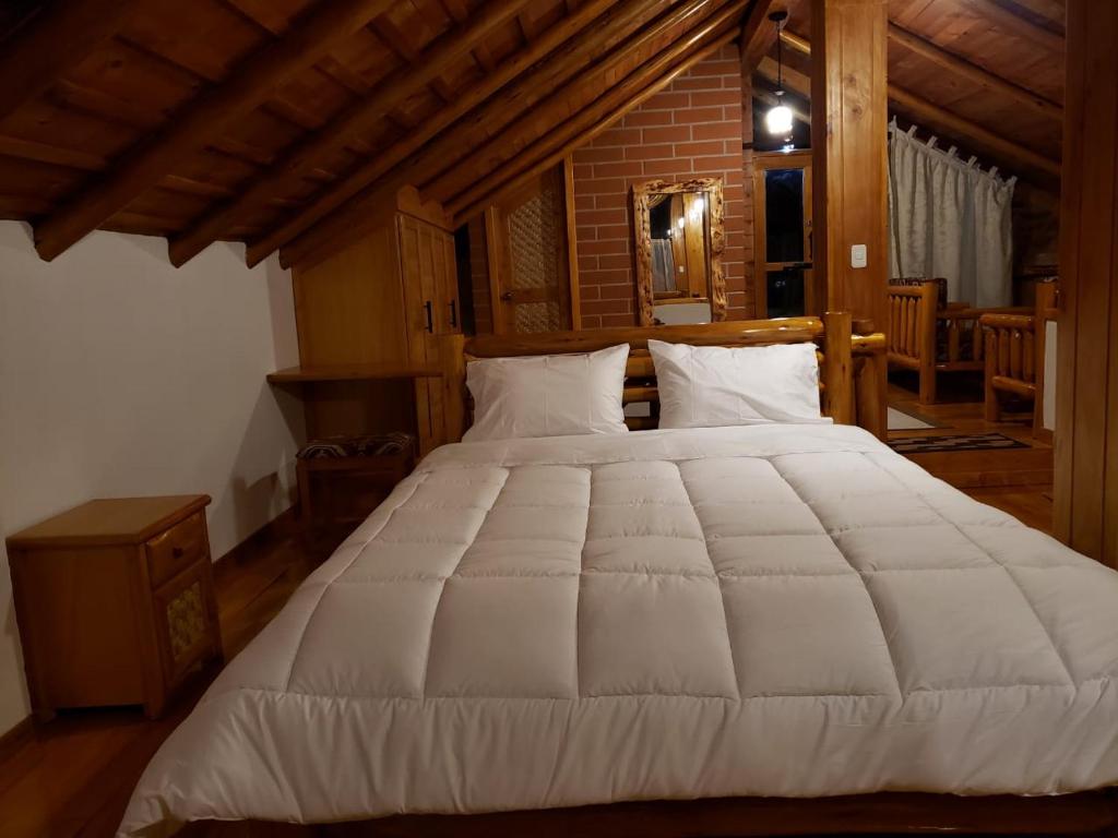 ein großes weißes Bett in einem Holzzimmer in der Unterkunft ATALLARO Hospedaje in Otavalo