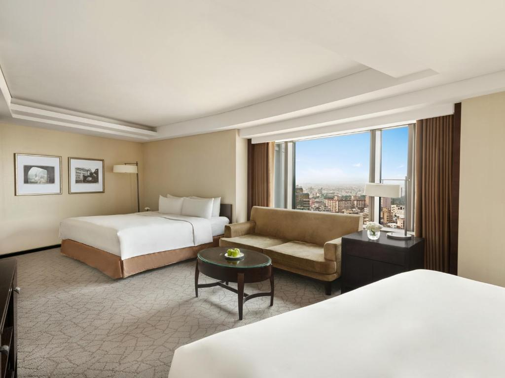 a hotel room with two beds and a couch at Shangri-La Far Eastern Tainan in Tainan