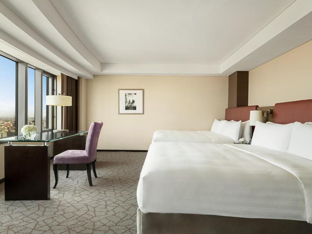 a hotel room with a large bed and a desk at Shangri-La Far Eastern Tainan in Tainan