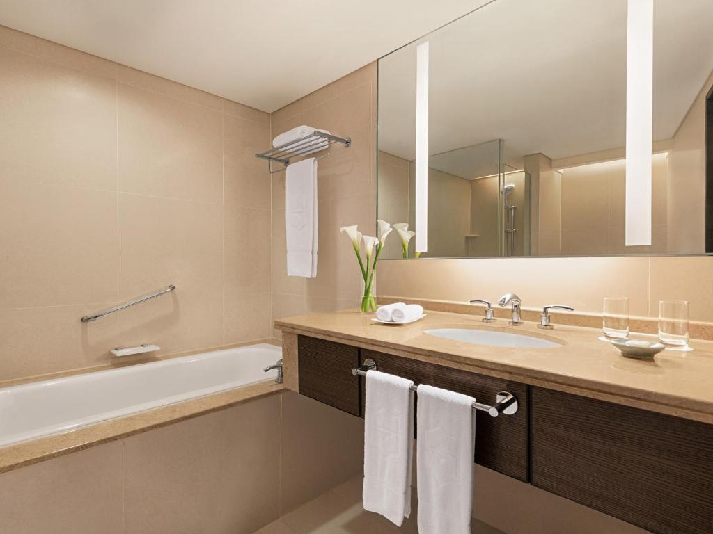 a bathroom with a sink and a tub and a mirror at Shangri-La Far Eastern Tainan in Tainan