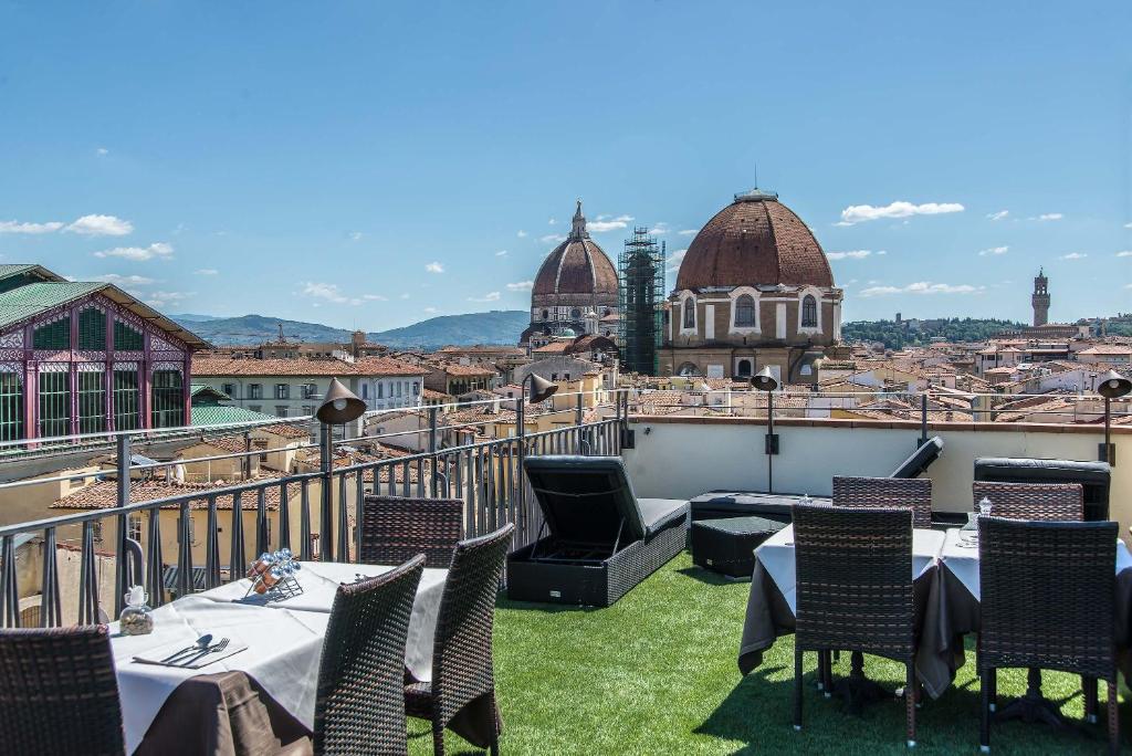 a patio area with chairs, tables, chairs and umbrellas at Hotel Machiavelli Palace in Florence