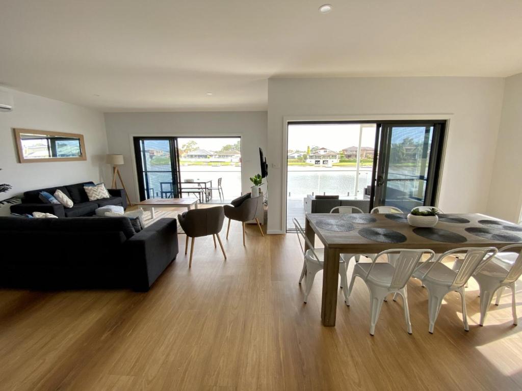 a living room with a couch and a table and chairs at Reflections on the water in Port Macquarie