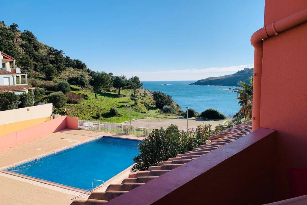 a swimming pool on the side of a house with the ocean at Appartement Vue Mer - 6 personnes in Cerbère