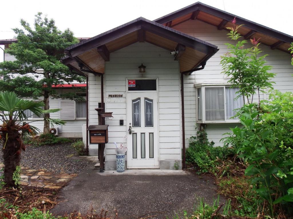 a small white house with a white door at ペンション　メタセコイア in Aiba