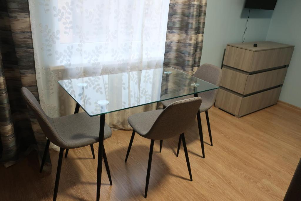 uma mesa de vidro e cadeiras num quarto com uma janela em Vienības 32 em Daugavpils