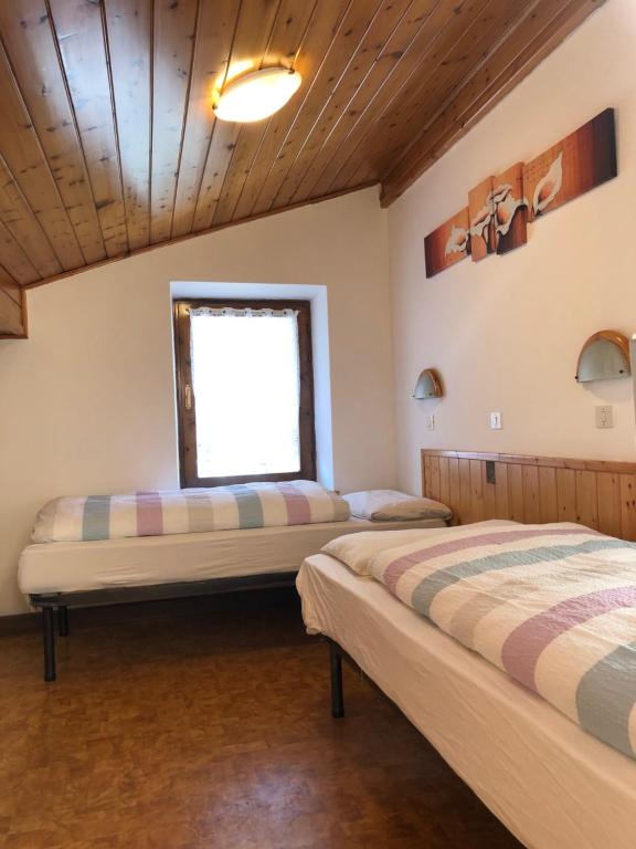 two beds in a room with a window at B&B Astor in Alleghe