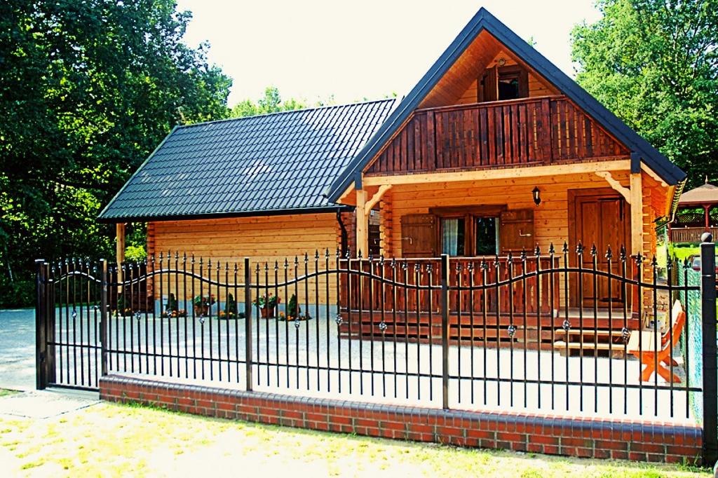 a wooden cabin with a fence in front of it at Domki z bali Deluxe in Jarosławiec