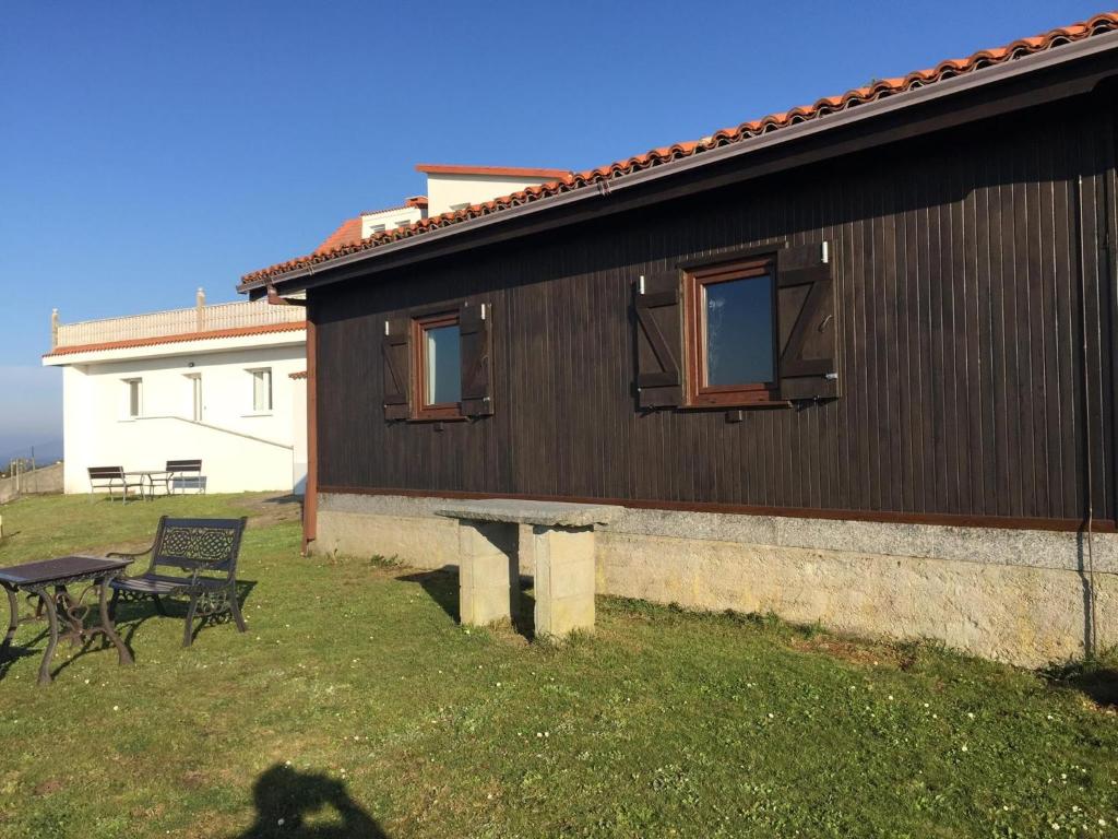 a house with a table and a bench next to it at Bungalow 2 (adosado) - Playa Arnela in Carballo