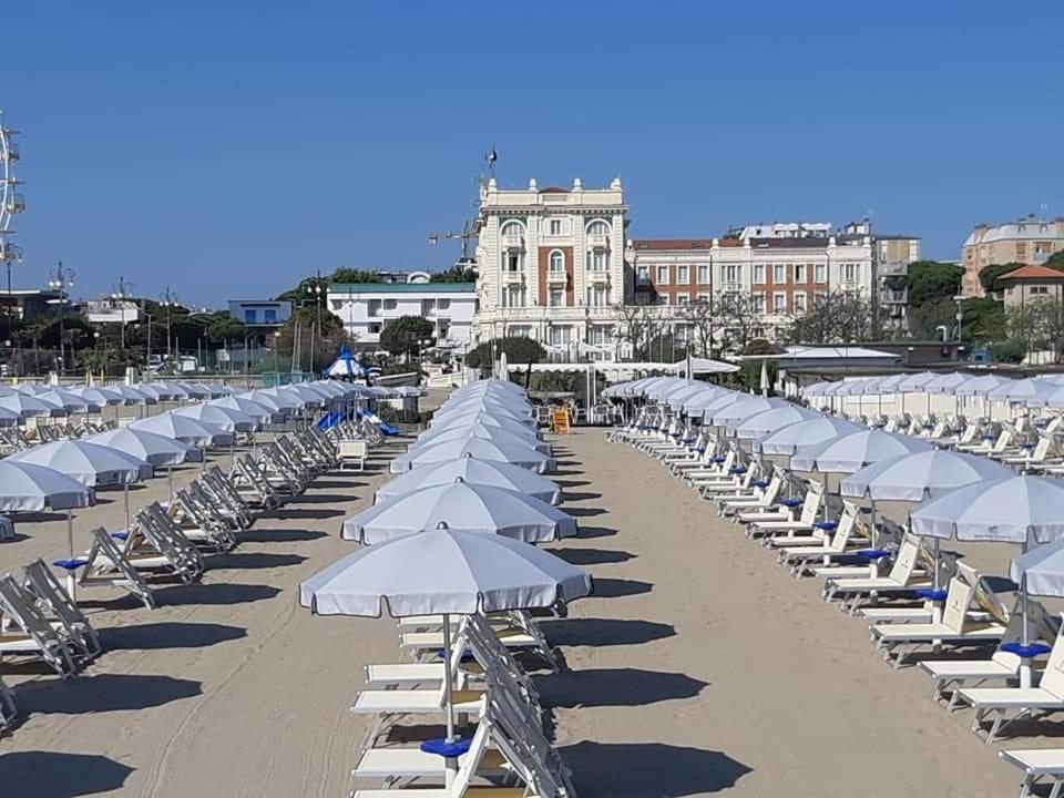 uma fila de cadeiras de praia e guarda-sóis numa praia em Grand Hotel Cesenatico em Cesenatico