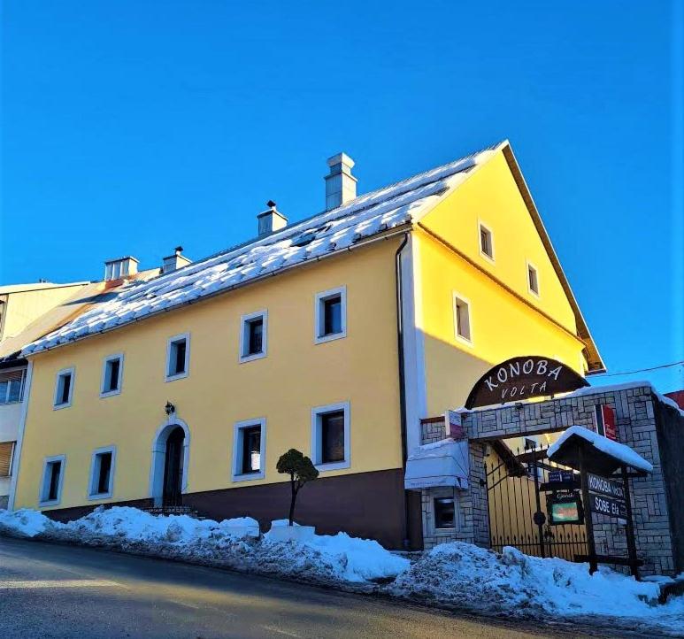 un edificio amarillo al lado de una calle en Sobe "Ela", en Fužine