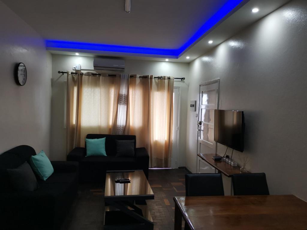 ein Wohnzimmer mit einem Sofa und einem TV in der Unterkunft TD Guest House 4 Plus in Chimoio