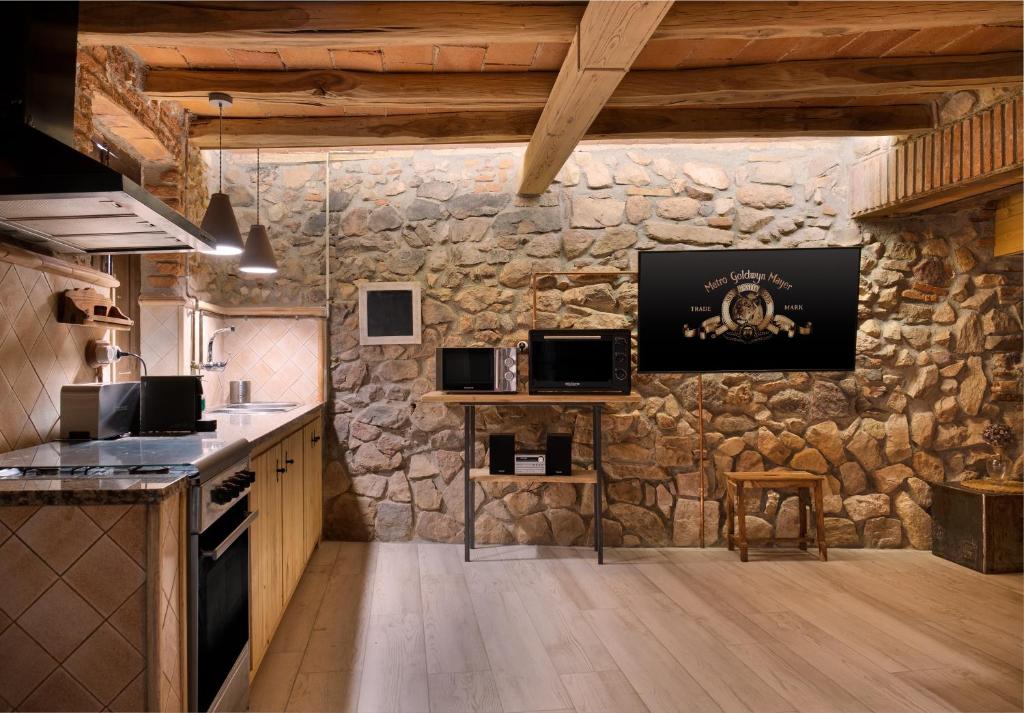 a kitchen with a stone wall with a tv on the wall at Masovería l'Era in Arbúcies