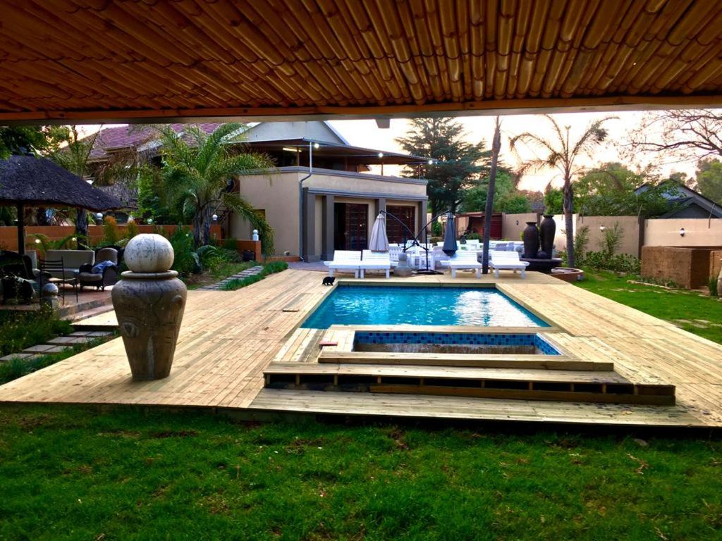 un patio trasero con piscina y una casa en The Afropolitan en Johannesburgo