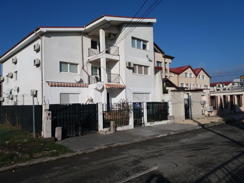 een wit huis met een hek naast een straat bij Apartament Kamino in Mamaia Nord – Năvodari