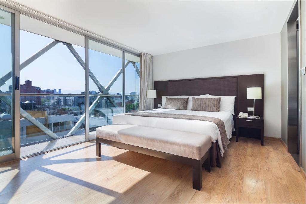 a bedroom with a large bed and a large window at Exe Suites Reforma in Mexico City