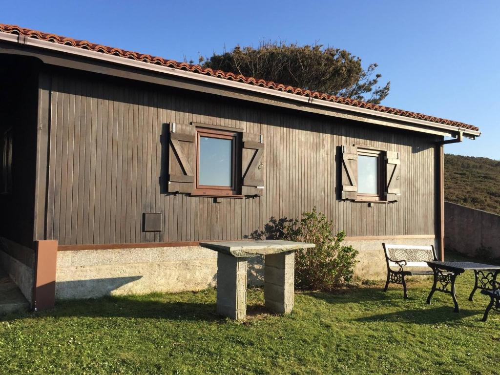 un edificio con dos ventanas y una mesa en el patio en Bungalow 3 (adosado) - Playa Arnela, en Carballo