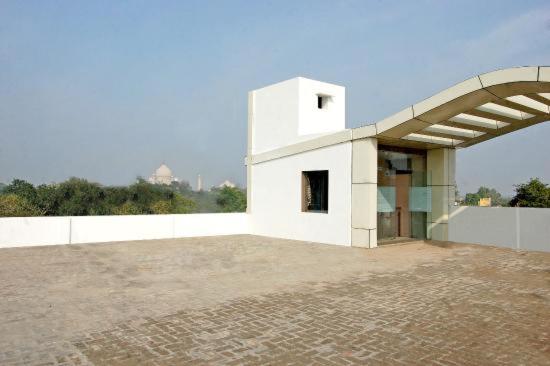 a white building with a roof and a brick floor at Hotel Rudra Vilas in Agra