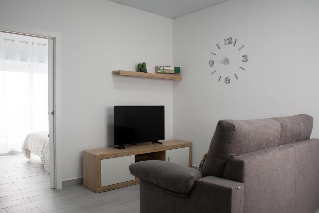 a living room with a chair and a tv and a clock at Apartamento Calma in Vejer de la Frontera