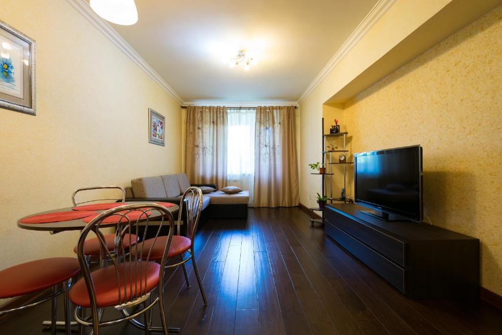 uma sala de estar com uma mesa com cadeiras e uma televisão em Nadezhda Apartment on Dostyk street 89 em Almaty