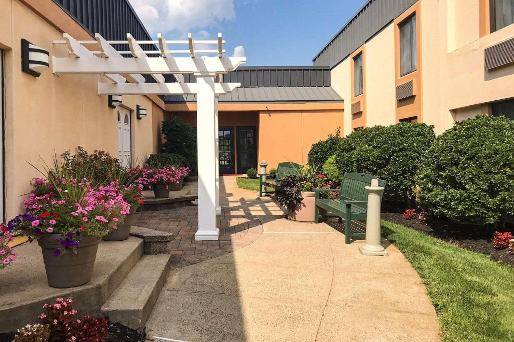 a white pergola next to a building with flowers at Clarion Hotel & Conference Center in Toms River