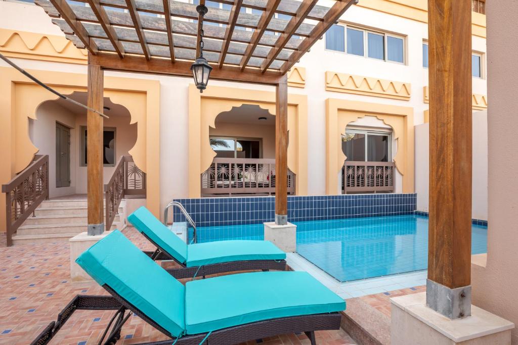 a house with a swimming pool with blue furniture at Exclusive Escapes Private Pool Homes and Villas by GLOBALSTAY Holiday Homes in Dubai