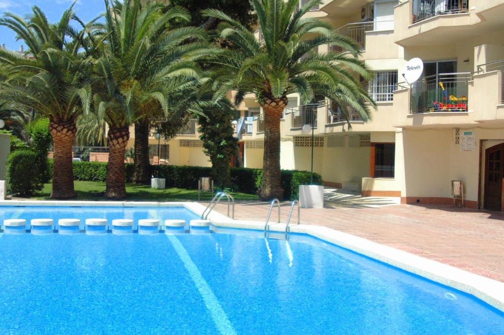 a swimming pool in front of a building with palm trees at Rentalmar Murillo Plus in Salou