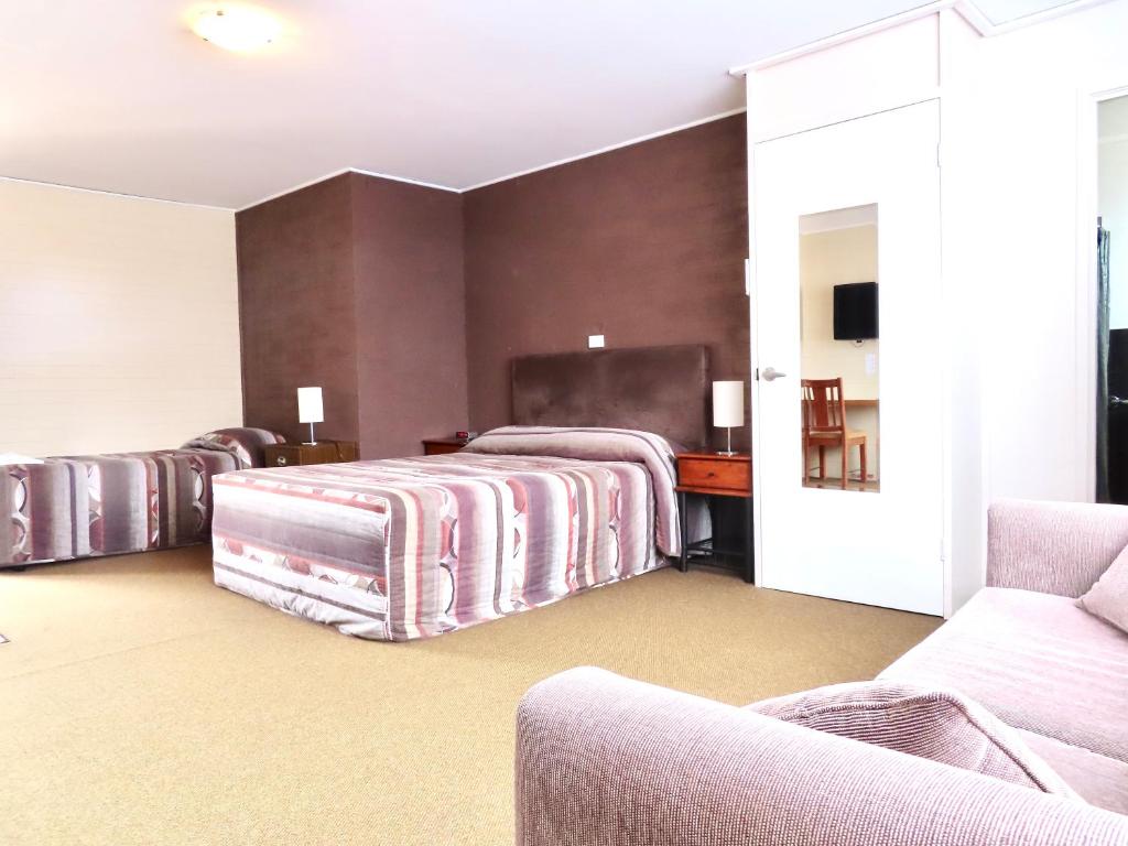 a hotel room with two beds and a desk at Wedderburn Goldseeker Motel in Wedderburn