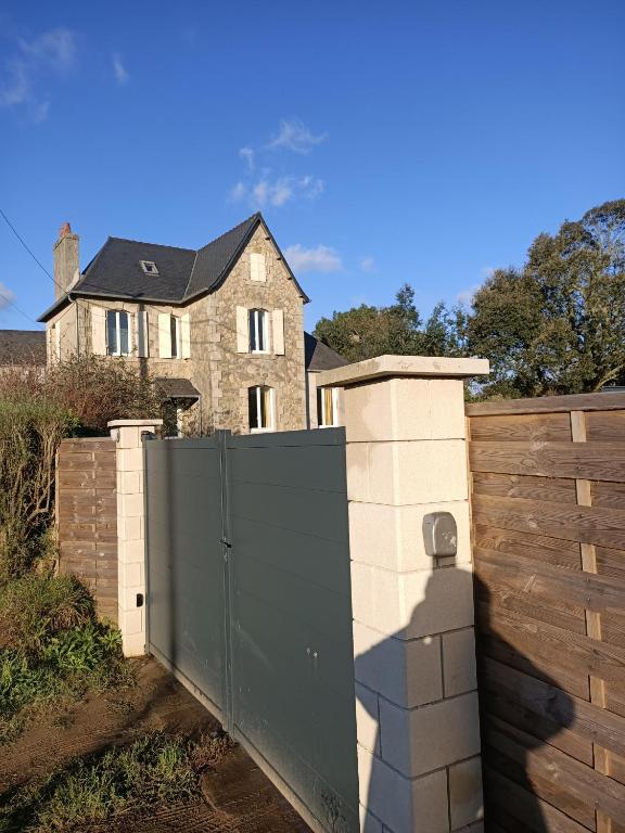 une clôture avec un portail en face d'une maison dans l'établissement Kermaravel, le petit manoir en bord de mer., à Saint-Pol-de-Léon