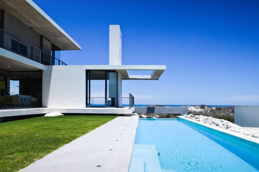 a villa with a swimming pool in front of a house at VAME Beachfront in Yzerfontein