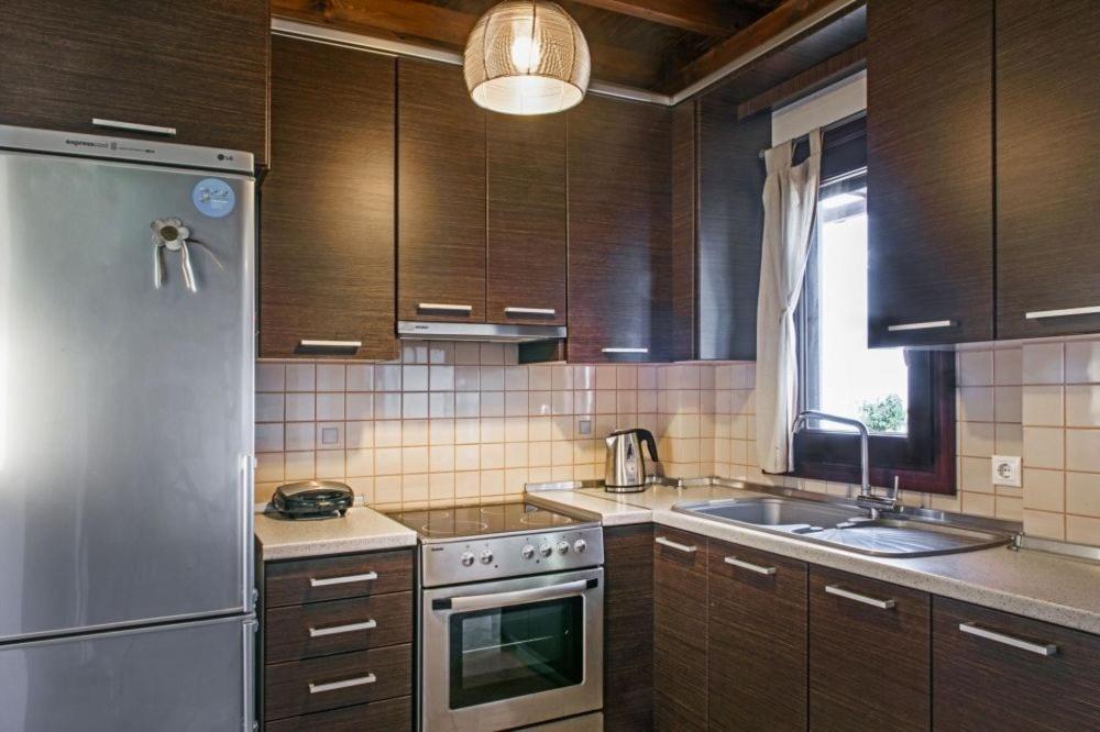 kuchnia z drewnianymi szafkami i lodówką ze stali nierdzewnej w obiekcie Katevi Luxury Seafront Villa w mieście Ierissós