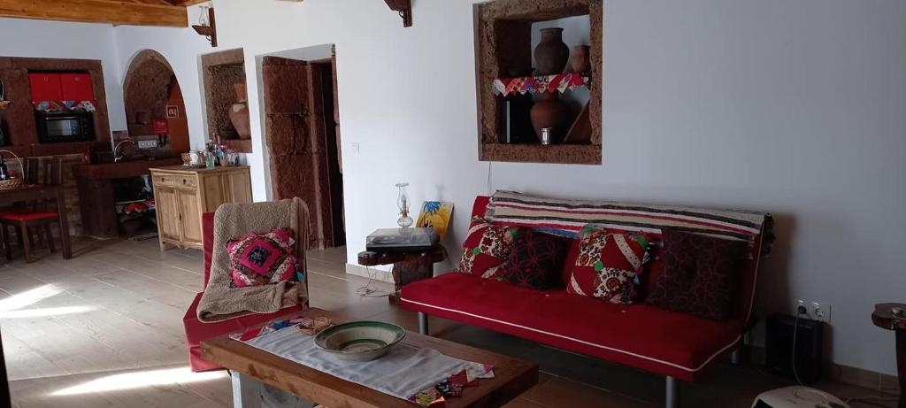 a living room with a red couch and a table at Casa da Bisa - Santa Maria - Açores in Santa Bárbara