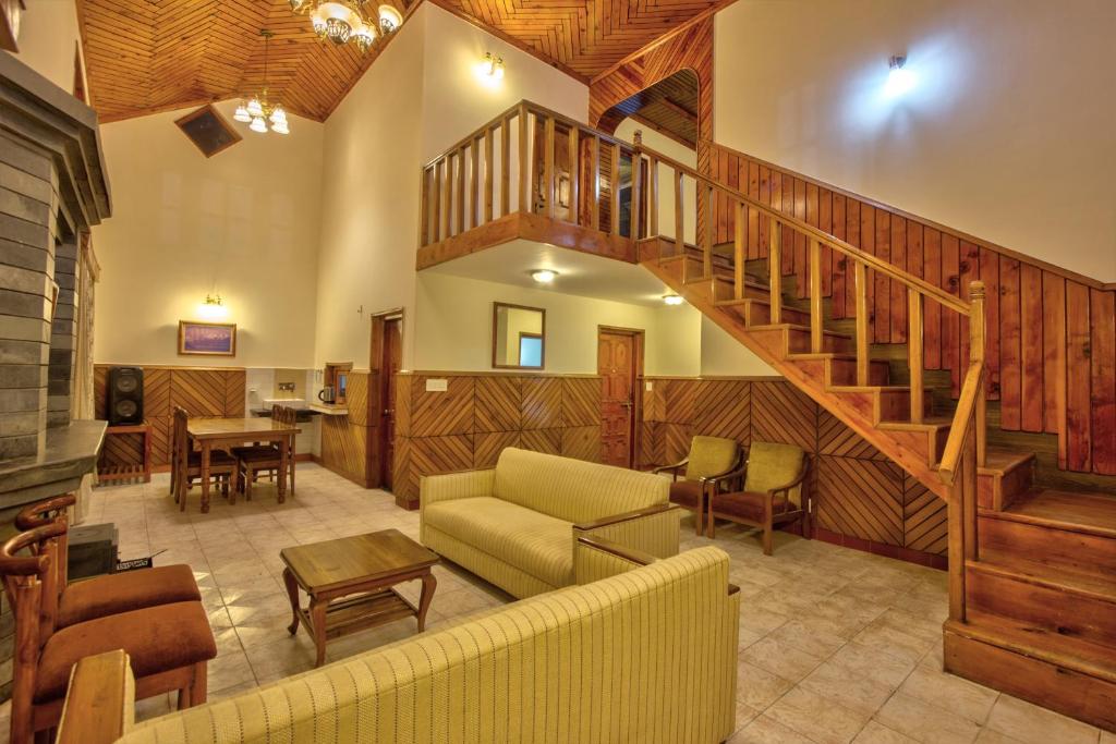 a living room with a staircase and a couch at Nature House in Manāli