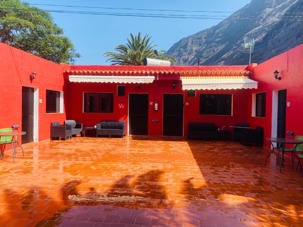 een rood huis met stoelen en tafels ervoor bij Pensión Casa Trudo in Frontera