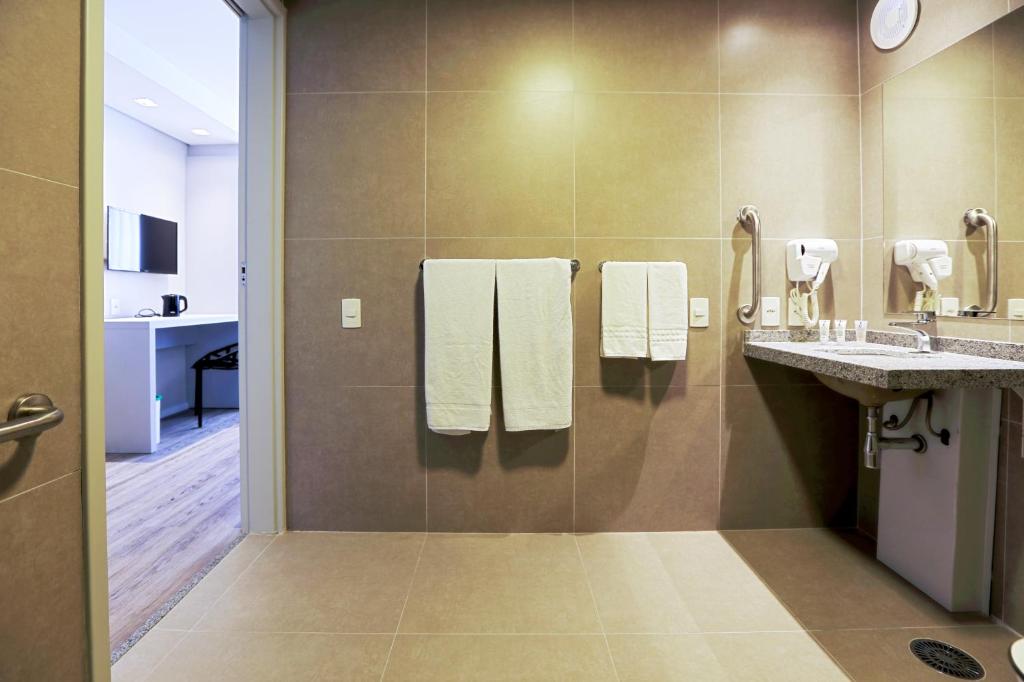 a bathroom with two sinks and two mirrors and towels at Comfort Hotel Guarulhos Aeroporto in Guarulhos