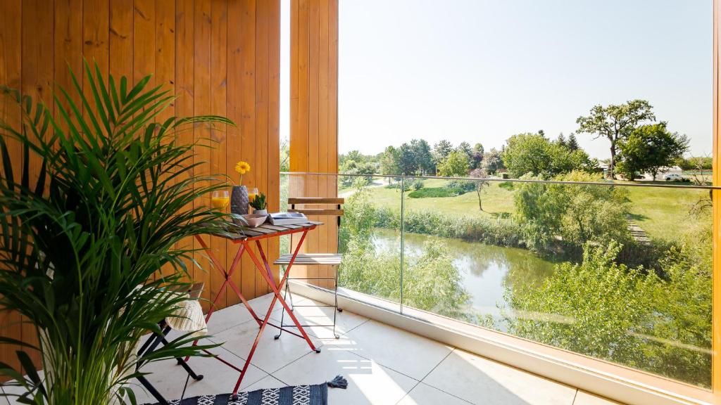 Il Lago - Azur - Cozy Luxurious Smart Home By The Lake في Voluntari: شرفة مع نافذة كبيرة مطلة على النهر