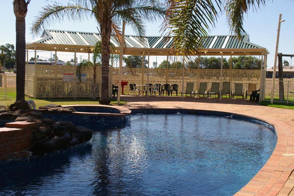 una piscina de agua con cenador y palmeras en Pines Country Club Motor Inn, en Shepparton