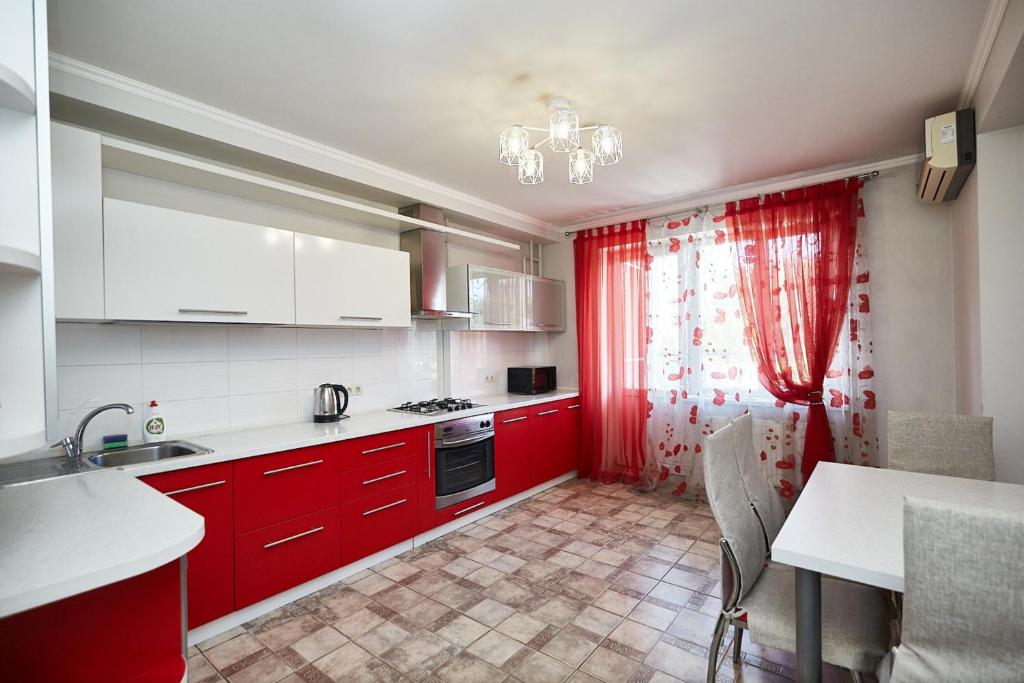a kitchen with red cabinets and a red curtain at Mitropolit Dosoftei Street Апартаменты in Chişinău