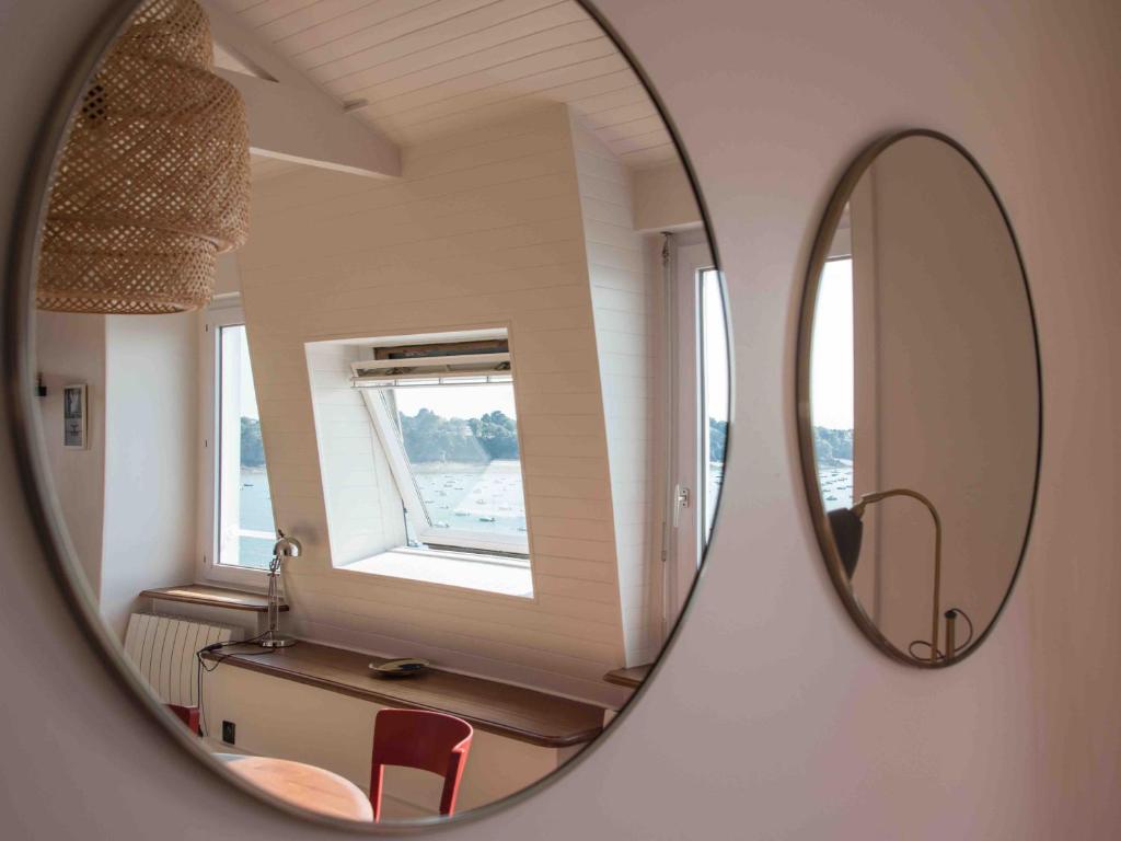 un miroir reflétant une chambre avec une table et une fenêtre dans l'établissement Dinard, très bel appartement***** avec vue sur mer, à Dinard
