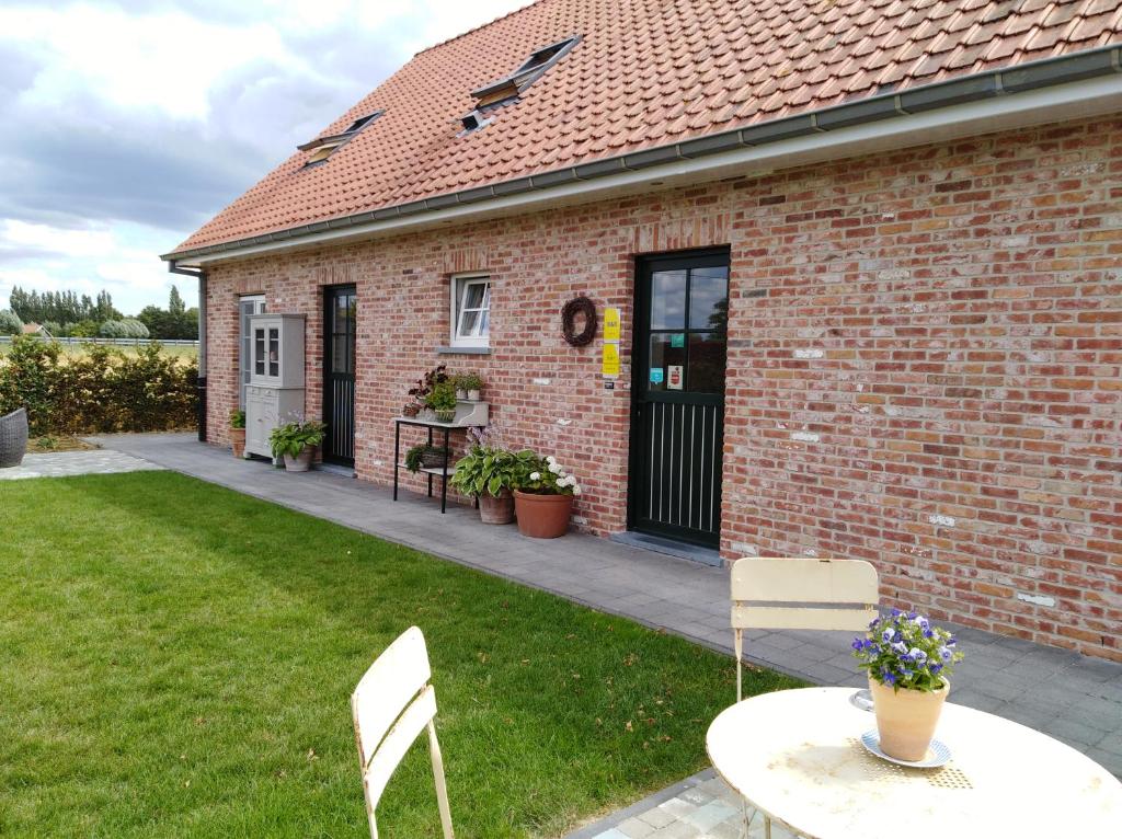 a brick house with a table and chairs in a yard at 't Hooghe Licht Bed & Breakfast in Zonnebeke