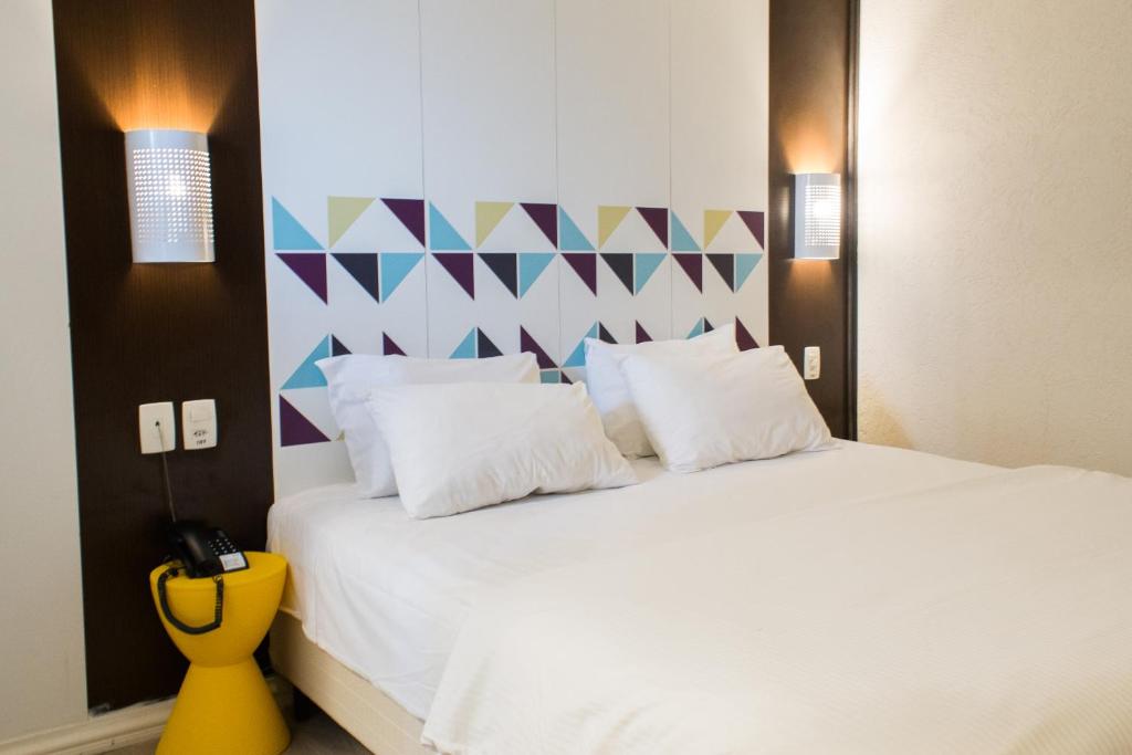 a bedroom with a white bed with a colorful wall at Master Express Moinhos de Vento in Porto Alegre