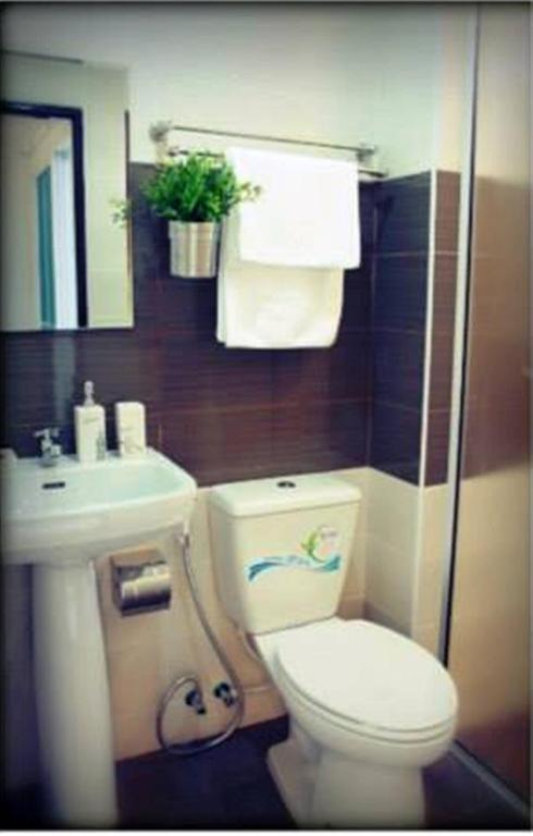 A compact bathroom with a toilet, pedestal sink and wall-mounted towel rail.