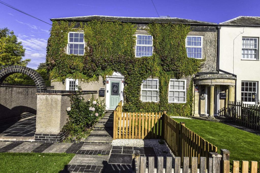 a house covered in ivy with a wooden fence at Greystones in Nottingham